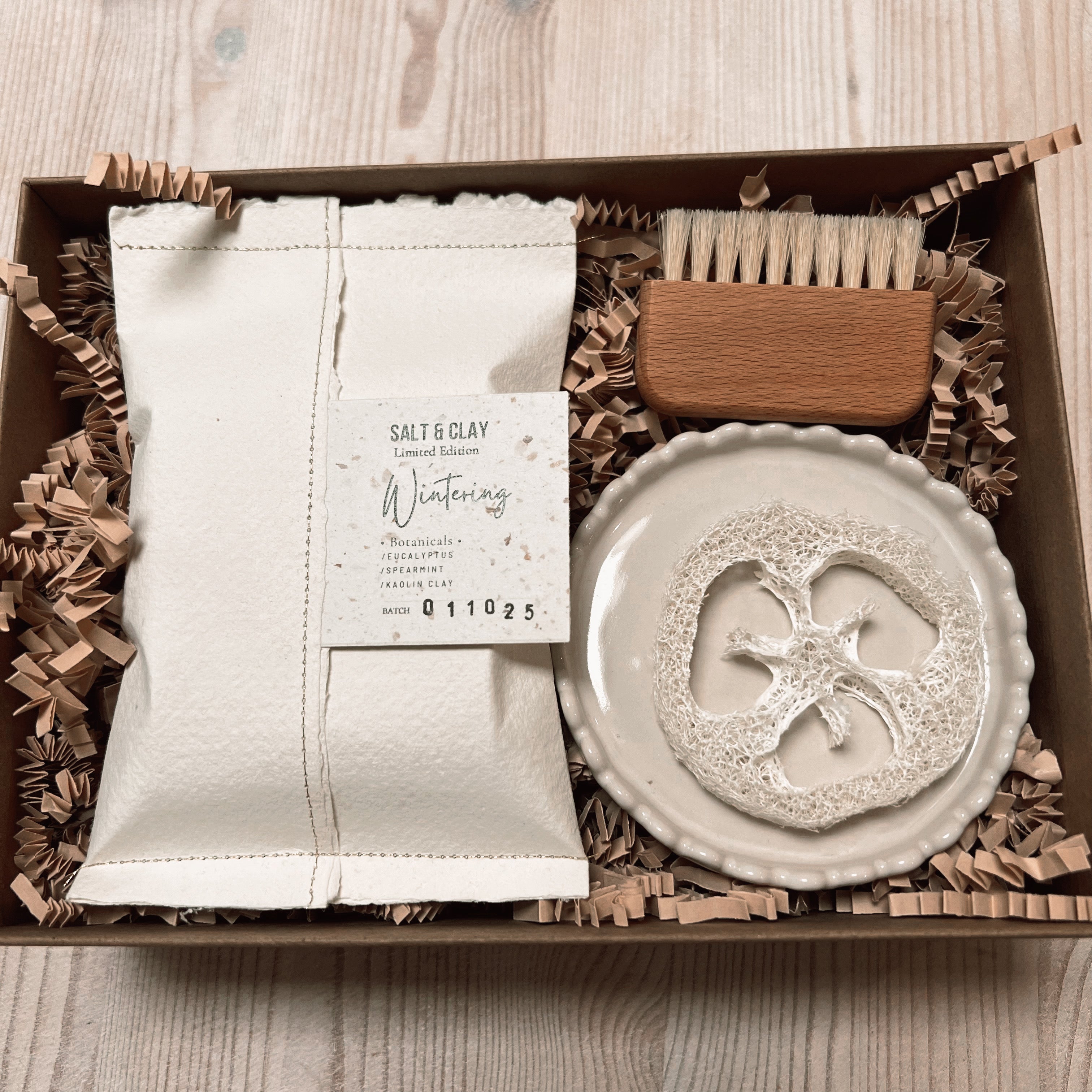 Gift set with soap in handmade white paper packaging. Ceramic soap dish with a scalloped edge.