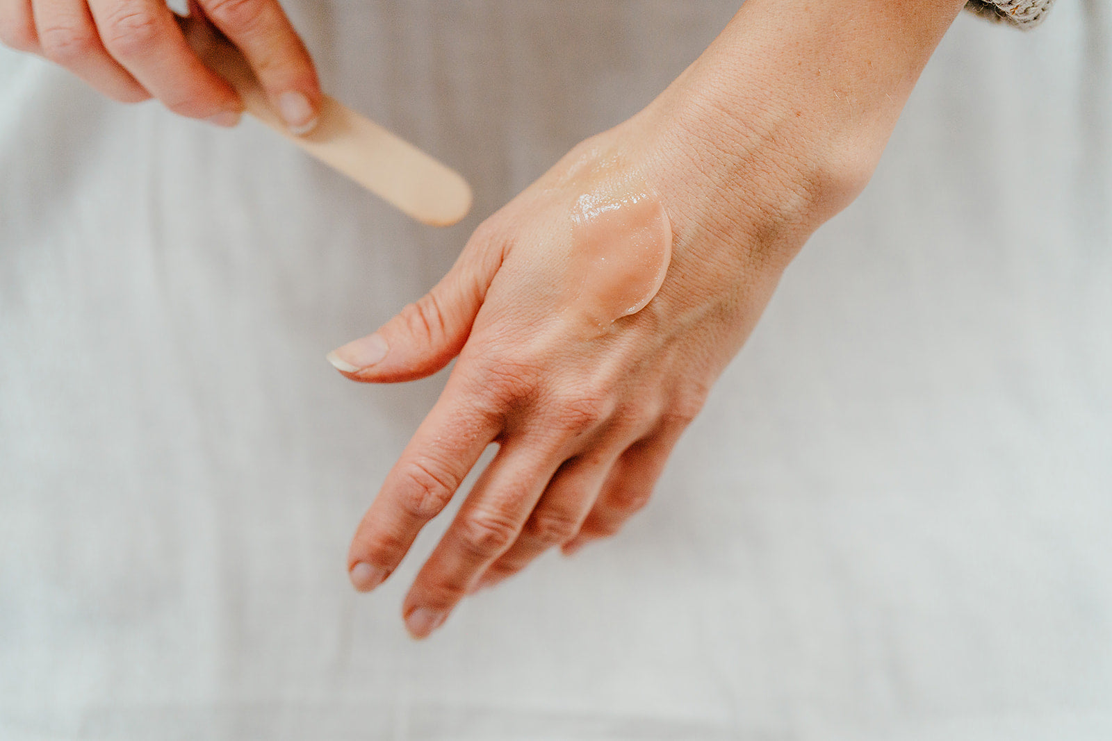 Image showing a scoop of our Brighten and Revive cleanser spread on a hand to show the creamy balm consistency. 