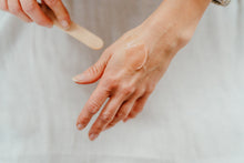 Load image into Gallery viewer, Image showing a scoop of our Brighten and Revive cleanser spread on a hand to show the creamy balm consistency. 
